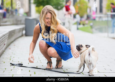 Jolie jeune femme joue avec un adorable carlin sur une route Banque D'Images