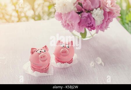 Gâteaux rose en forme de petite piggies avec un bouquet de pivoines pour les vacances. Copier l'espace. Banque D'Images