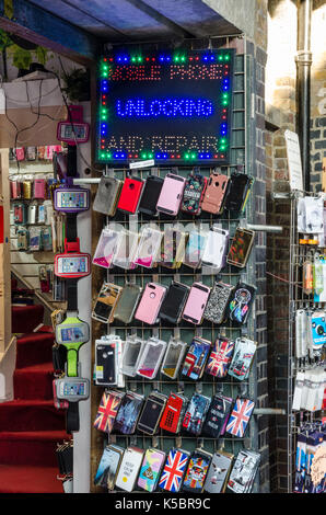 Un rack avec un téléphone mobile, housses et accessoires affichés à l'extérieur d'un magasin. Banque D'Images