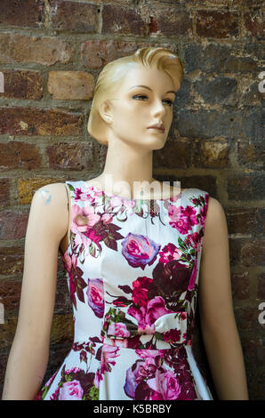Une boutique mannequin vêtue d'une robe blanche avec ref floral design se tient en face d'un mur de briques à Camden Market, Londres. Banque D'Images