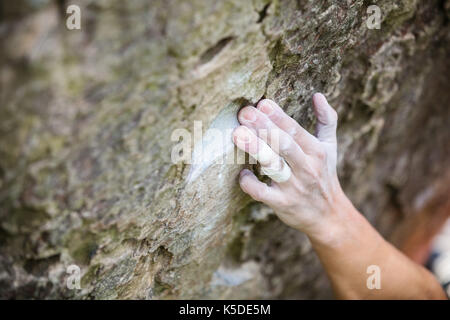 Rock Climber's main agrippant petite attente sur falaise naturelle, faible profondeur de champ Banque D'Images