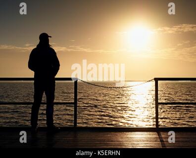 Des profils homme grand conseil sur la jetée au-dessus de la mer pour regarder le soleil du matin. bon niveau d'eau dans la baie. vivid et fort effet de vignettage. Banque D'Images