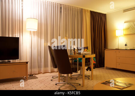 Vienne, Autriche - avril 28th, 2017 : soirée romantique avec bouteille de vin rouge, de sucreries et de fruits dans la chambre d'hôtel de luxe sur une table avec trois chaises en cuir, hilton suite penthouse Banque D'Images