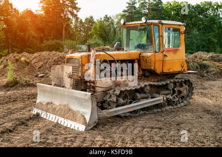 Ancien travail d'excavateur le défrichage au coucher du soleil d'une journée ensoleillée. La structure horizontale. Banque D'Images