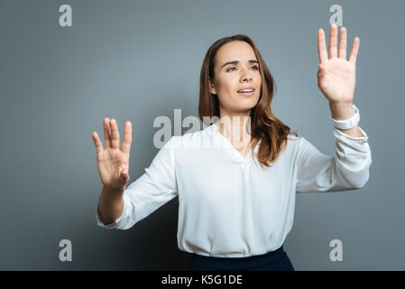 Excité joyeuse femme debout contre l'arrière-plan gris Banque D'Images