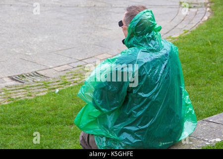 Swanage, Dorset, UK. Sep 9, 2017. Météo France : forte pluie et tonnerre à Swanage. Homme assis sur un mur en poncho imperméable vert. Credit : Carolyn Jenkins/Alamy Live News Banque D'Images