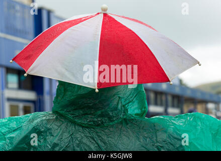 Swanage, Dorset, UK. Sep 9, 2017. Météo France : forte pluie et tonnerre à Swanage. Vue arrière de personne qui porte de douche vert et rouge poncho et parapluie blanc sous la pluie. Credit : Carolyn Jenkins/Alamy Live News Banque D'Images