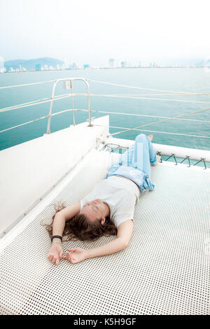 Jeune femme se coucha sur le pont des navires de croisière lors d'un voyage à la mer Banque D'Images