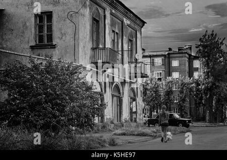 Vieux blocs d'une petite ville. Une fille avec un chien marcher par un vieux bâtiment abandonné. Banque D'Images