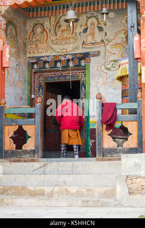 Moine laïcs entre dans le temple bouddhiste en ura, ura (mang gi lakhang) Bhoutan central. Banque D'Images