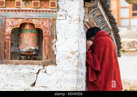 Villager tourne roues de prière à l'extérieur du temple bouddhiste en ura, ura (mang gi lakhang) Bhoutan central. Banque D'Images