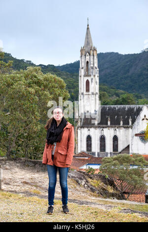 Jeune fille de dix-huit ans qui pose pour un portrait souriant en face de Caraca du sanctuaire d'église néo-gothique, Minas Gerais, Brésil Banque D'Images