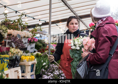 Vendeur vend des fleurs à un client à un stand de fleurs au marché de la Bastille à Paris, France Banque D'Images