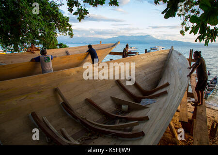 Les constructeurs de bateaux d'observer leurs travaux sur la plage à l'île de Bunaken, Sulawesi Banque D'Images