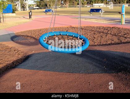 Tube rond de couleur bleue au swing d'un parc. Banque D'Images