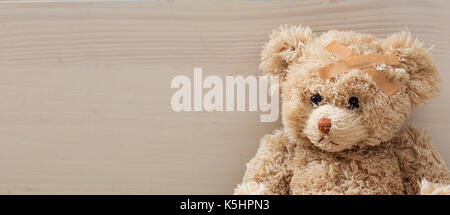L'enfant est malade concept.ours avec bandage assis sur un sol en bois Banque D'Images