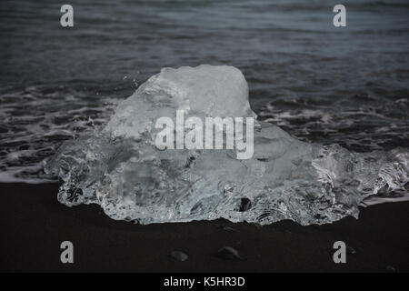 Morceau de glace des glaciers étincelants clairement rejetés sur la plage de sable noir Banque D'Images