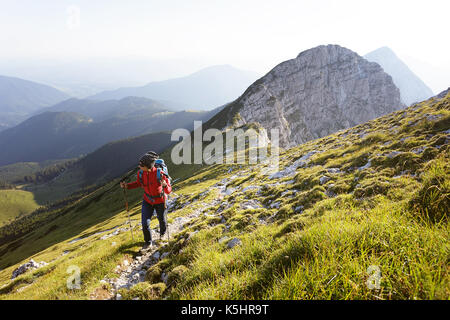 Femme en jeans et blouson rouge randonnées sur les pentes couvertes d'herbe et de rochers. Kladivo Karavanke,, en Slovénie. Banque D'Images