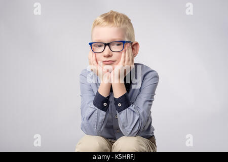 Portrait of caucasian garçon blond dans les verres à ennuyer avec l'expression du visage à l'appareil photo sur fond blanc. Banque D'Images