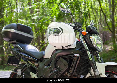 Photo d'une moto garée sur une route de campagne dans une forêt Banque D'Images