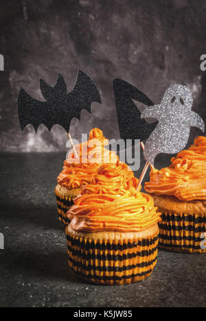 Idée simple de funny kid's traiter pour l'halloween : gâteaux à la citrouille avec crème, avec des décors sous forme de symboles de vacances - fantôme, sorcière, bat. sur un bl Banque D'Images