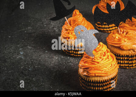 Idée simple de funny kid's traiter pour l'halloween : gâteaux à la citrouille avec crème, avec des décors sous forme de symboles de vacances - fantôme, sorcière, bat. sur un bl Banque D'Images