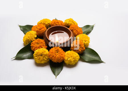 Rangoli fleur pour diwali ou pongal ou faite à l'aide de l'œillet d'Onam ou zendu fleurs et pétales de rose rouge sur fond blanc avec diwali diya au milieu Banque D'Images