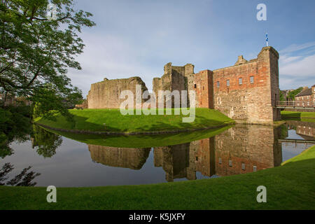 Vue imprenable de 13e siècle le château de Rothesay avec de hauts murs de pierre reflètent dans l'eau de surface miroir en douves sous ciel bleu, l'île de Bute en Ecosse Banque D'Images