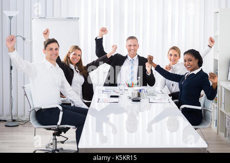Group of smiling multi ethnic woman raising arms in office Banque D'Images