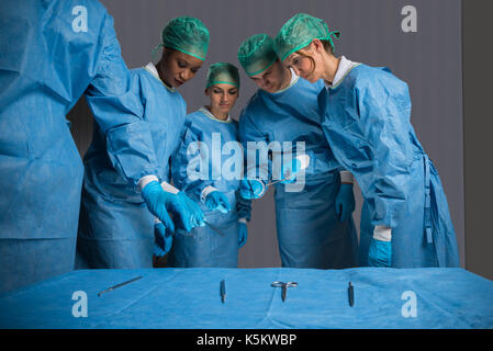 Hommes et femmes chirurgiens Holding Medical Instruments en salle d'opération Banque D'Images