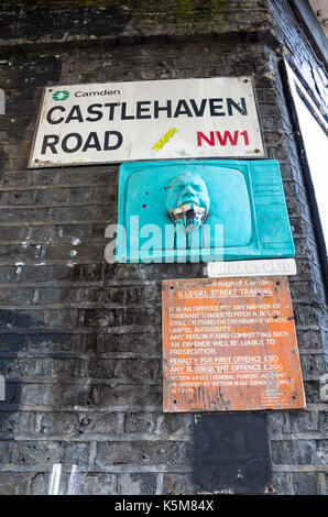 Ci-dessous le nom de la rue signe pour Castlehaven Road à Camden Town, Londres, est un petit morceau d'art de rue et un avis juridique à propos de commerce de rue illégales Banque D'Images