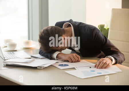 Assez jeune businessman sleeping on desk in office Banque D'Images