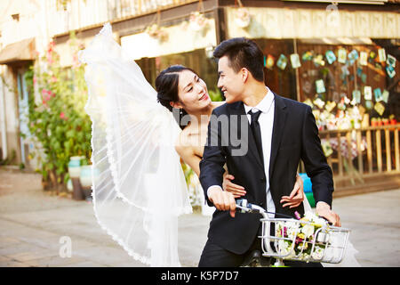 Asiatique romantique newly wed couple having fun riding a bicycle ensemble. Banque D'Images