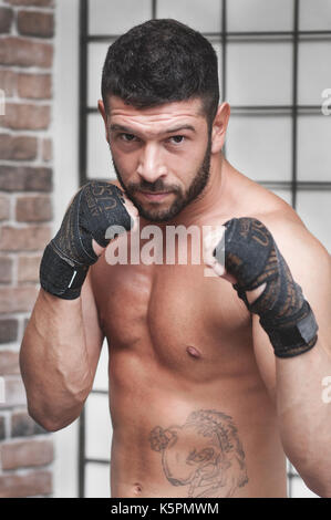 Portrait of muscular male boxer posant en boxe position contre l'arrière-plan de la grille. Banque D'Images