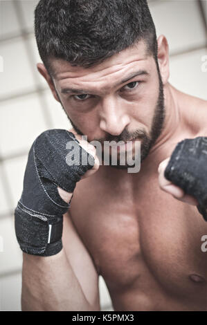 Portrait of muscular male boxer posant en boxe position contre l'arrière-plan de la grille. Banque D'Images