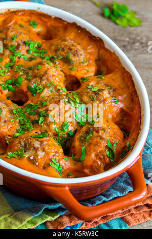 Boulettes de viande au four avec la sauce tomate et le persil dans le plat de cuisson sur fond de bois rustique Banque D'Images