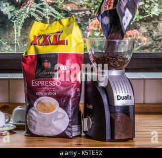 Café en grains est versé dans un broyeur électrique Princess, avec du café moulu dans le contenant, et une restauration de pack XXL Espresso en grains à quai. Banque D'Images