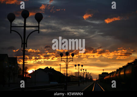 Un train passe sur les voies à la station i au cours d'un beau lever de soleil. Banque D'Images