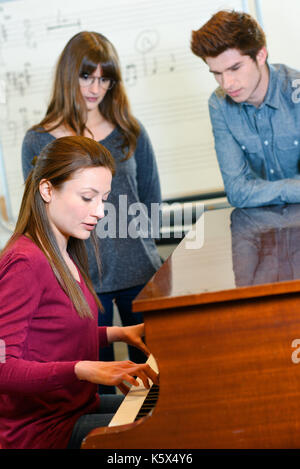 Un professeur de musique avec deux élèves pendant la leçon de piano Banque D'Images