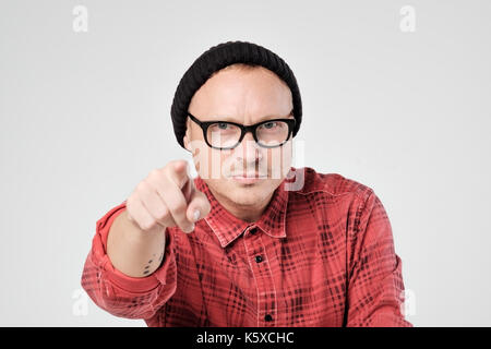 Un jeune homme en chapeau noir et verres comme hipster regarde la caméra en déplaisir. Il strechs part à venir. Banque D'Images