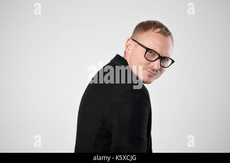 Smiling young man in black vêtements standing against white background Banque D'Images