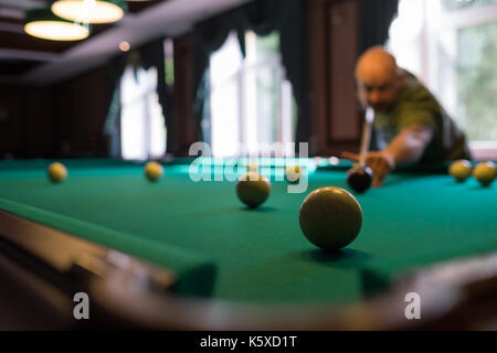 Jeune homme jouant au billard à l'intérieur. Passer du temps libre au jeu Banque D'Images