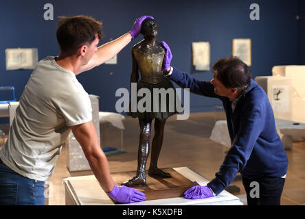 La sculpture en bronze « Little Dancer aged 14ans » d'Edgar Degas est mise en place par Tim Matthews (à gauche) et Nik Zolman (à droite) faisant partie d'une nouvelle exposition, « Degas: A passion for Perfection », au Fitzwilliam Museum de Cambridge. Banque D'Images