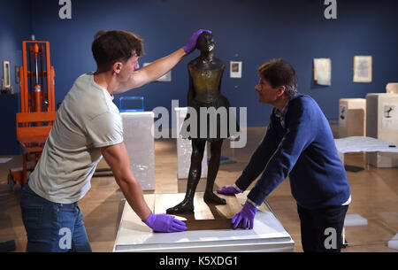 La sculpture en bronze « Little Dancer aged 14ans » d'Edgar Degas est mise en place par Tim Matthews (à gauche) et Nik Zolman (à droite) faisant partie d'une nouvelle exposition, « Degas: A passion for Perfection », au Fitzwilliam Museum de Cambridge. Banque D'Images
