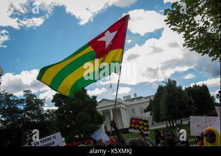 Un drapeau national Togo vu en face de la Maison Blanche. Une petite foule se rassemble en face de la Maison Blanche pour protester contre le dictateur togolais Faure Gnassingbe.Avant son élection, il a été nommé par son père, le Président Gnassingbé Eyadéma, en tant que ministre de l'équipement, des Mines, des postes et télécommunications, servant de 2003 à 2005. À la suite du décès du Président Eyadéma Gnassingbé en 2005, a immédiatement été installé à la présidence avec le soutien de l'armée. Des doutes sur la légitimité constitutionnelle de la succession conduit à de lourdes pressions régionales mis sur Gnassingbé, et il a ensuite démissionné o Banque D'Images