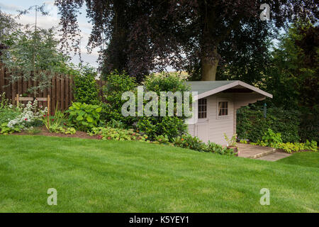 Belle, privé, traditionnelle, paysagée, country garden, West Yorkshire, Angleterre, Royaume-Uni - frontière herbacées et des plantes à fleurs, pelouse et remise. Banque D'Images