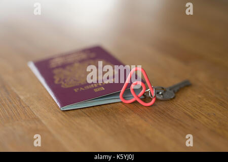 Un porte-clés de marque Airbnb avec un passeport britannique sur une table en bois haut. Banque D'Images