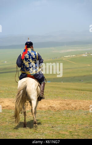 Oulan-bator, Mongolie - 12 juin 2007 : arrière d'un homme en vêtements traditionnels de Mongolie à cheval en haut de la colline à la recherche à vue sur la steppe au c Banque D'Images