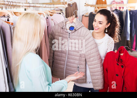 Deux jolies copines choisir veste chaude dans shop and smiling Banque D'Images