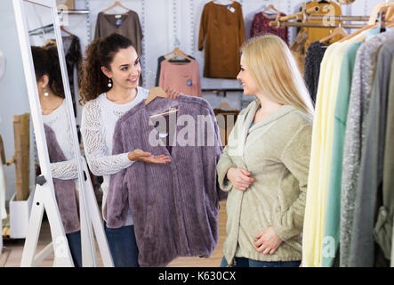 Jolie petite amie choisir veste chaude en magasin et smiling Banque D'Images